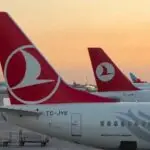 Several Turkish Airlines planes with red tails and white logos parked on the airport tarmac at sunset.